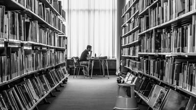 Eine Person sitzt in einer Bibliothek und liest